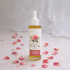 Bottle of Renewal Body Oil with rose petals on a textured surface

